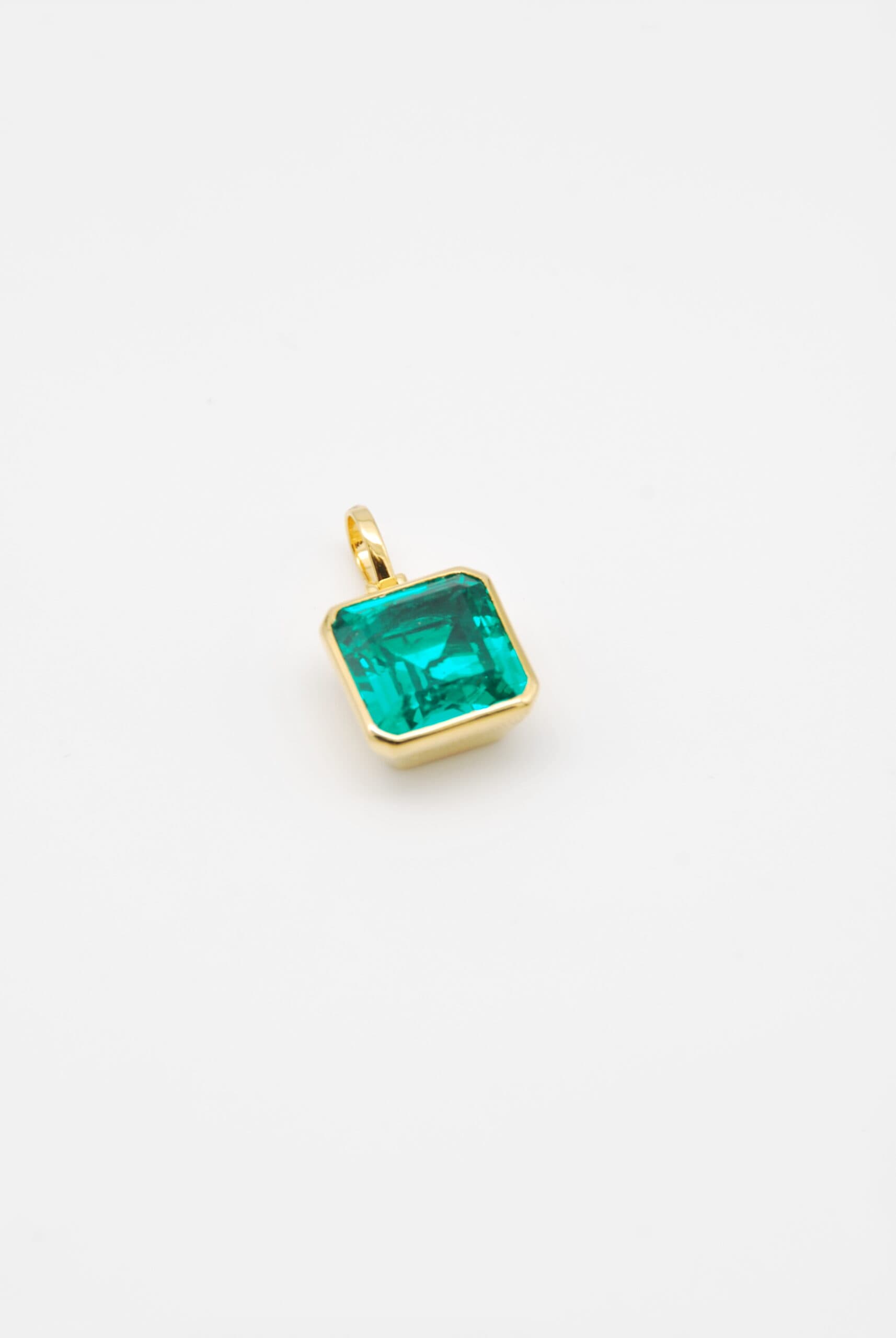 Yellow gold pendant bezel-set with an emerald-cut green stone